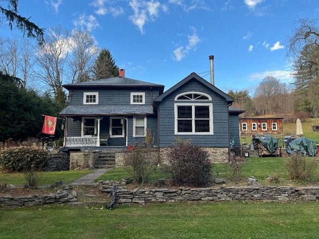 view of front facade with a porch, a chimney, and a yard