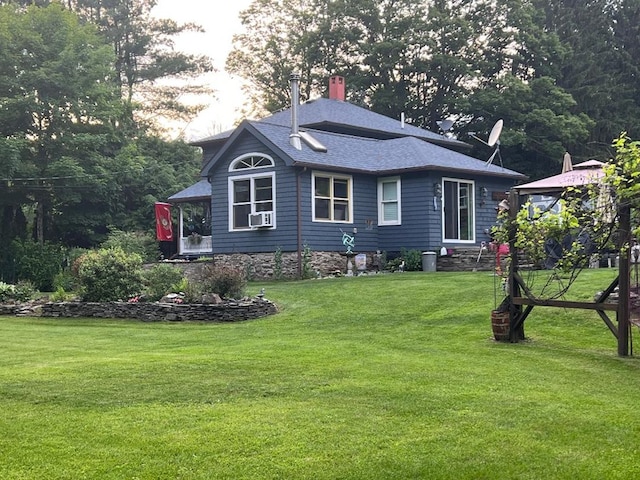 view of side of property with a lawn, cooling unit, a chimney, and roof with shingles