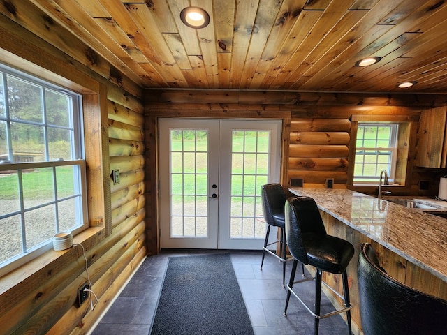 entryway with sink, wooden ceiling, rustic walls, and french doors