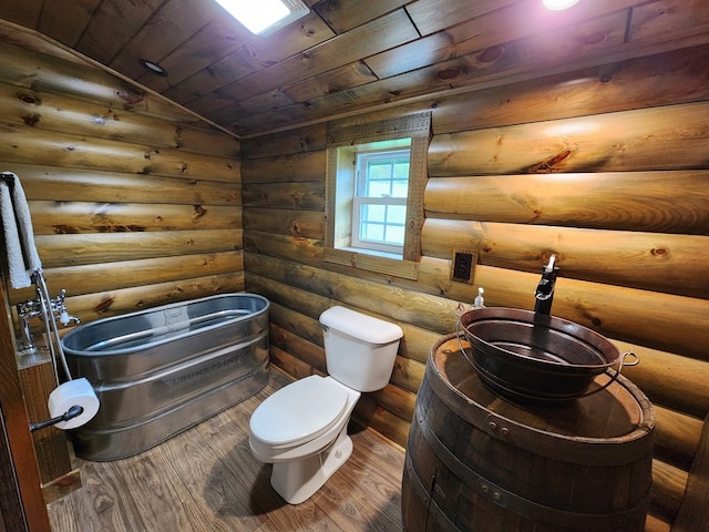 bathroom featuring hardwood / wood-style flooring, wood ceiling, log walls, and vaulted ceiling