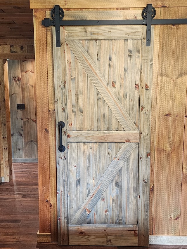 interior details with a barn door, wood-type flooring, and wooden walls