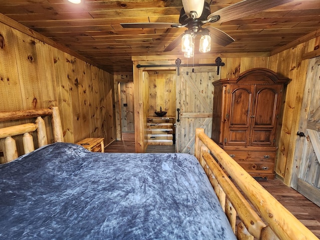 bedroom with a barn door, ceiling fan, wooden walls, and wood ceiling