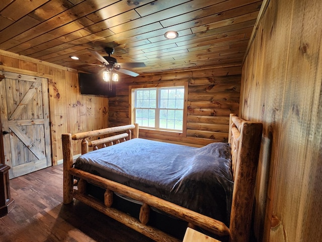 bedroom with ceiling fan, wooden ceiling, rustic walls, and dark wood-type flooring