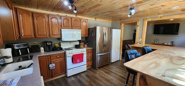 kitchen featuring dark hardwood / wood-style flooring, rail lighting, white appliances, sink, and wooden ceiling