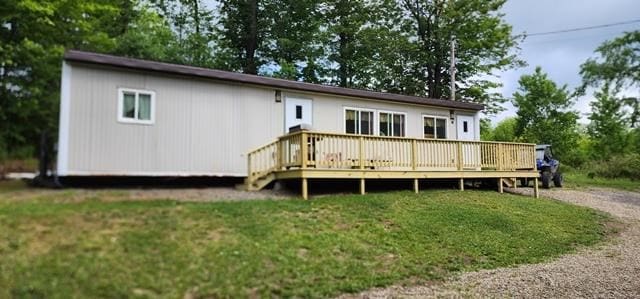 back of property featuring a wooden deck and a yard