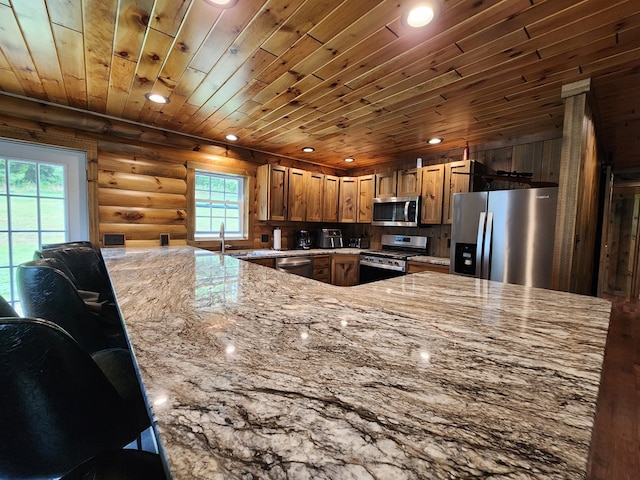 kitchen with rustic walls, appliances with stainless steel finishes, light stone counters, kitchen peninsula, and wood ceiling