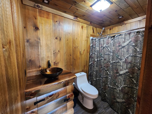 bathroom with wooden walls, sink, wood-type flooring, wooden ceiling, and toilet