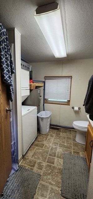 bathroom with a textured ceiling, vanity, stacked washer / drying machine, and toilet