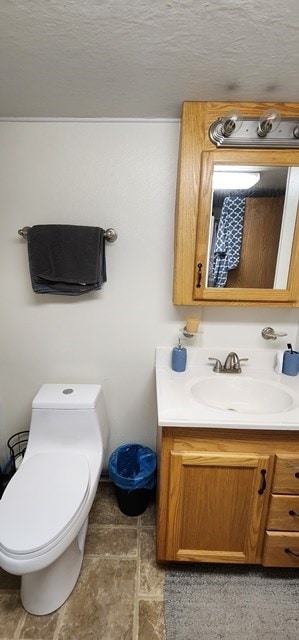 bathroom with a textured ceiling, vanity, and toilet