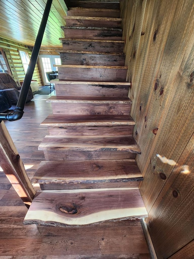 staircase featuring log walls and hardwood / wood-style floors