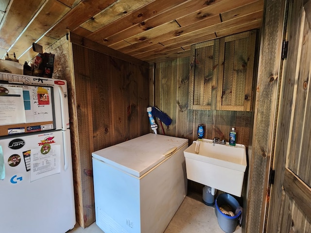 clothes washing area featuring wood ceiling, sink, and wooden walls