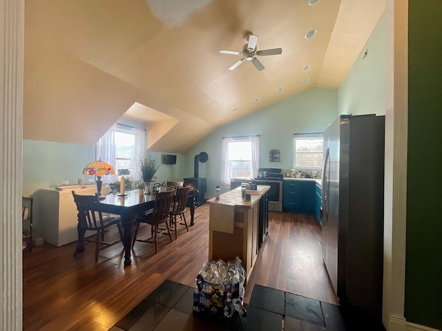 dining area featuring ceiling fan, a wood stove, dark hardwood / wood-style flooring, and lofted ceiling