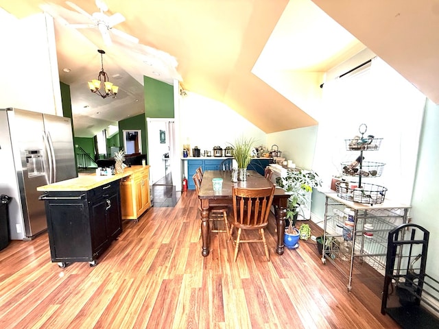 kitchen with vaulted ceiling, stainless steel fridge with ice dispenser, a kitchen island, and light hardwood / wood-style flooring