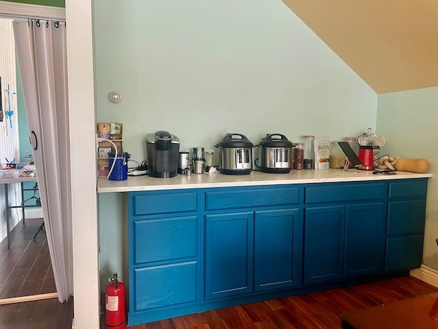 kitchen with vaulted ceiling, blue cabinets, and dark hardwood / wood-style floors