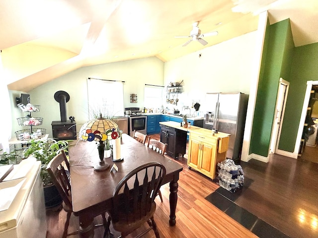 dining area with vaulted ceiling, a wood stove, ceiling fan, and light hardwood / wood-style floors