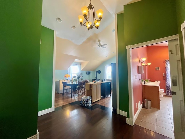 interior space featuring lofted ceiling, wood-type flooring, and ceiling fan with notable chandelier