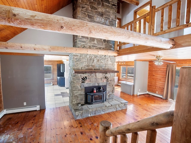 unfurnished living room with beamed ceiling, high vaulted ceiling, a wood stove, and wood-type flooring