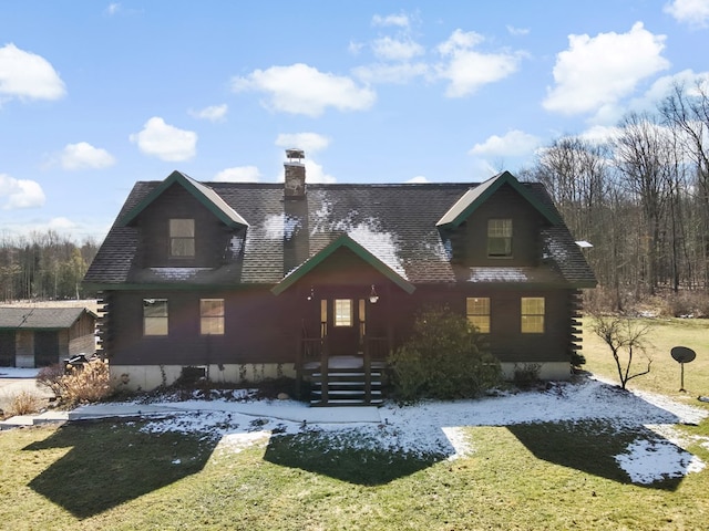 view of front of house featuring log siding, a front yard, and a chimney