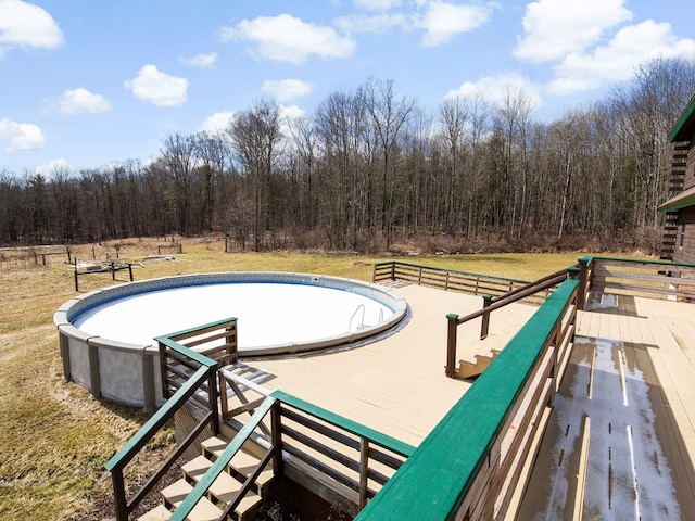 view of pool with a lawn and a forest view