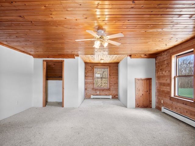 empty room featuring wooden walls, carpet, a baseboard heating unit, wooden ceiling, and baseboard heating