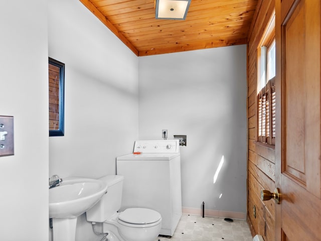 half bathroom with washer / dryer, toilet, wood ceiling, and baseboards