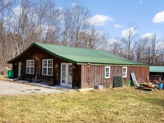 exterior space featuring a lawn, french doors, and metal roof