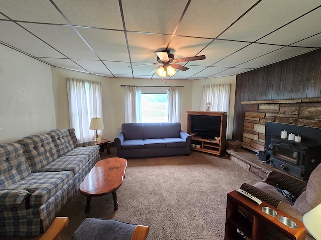 258 Pleasant Stream Rd, Trout Run, PA 17701 - living area featuring a wood stove, ceiling fan, carpet flooring, a paneled ceiling, and wood walls