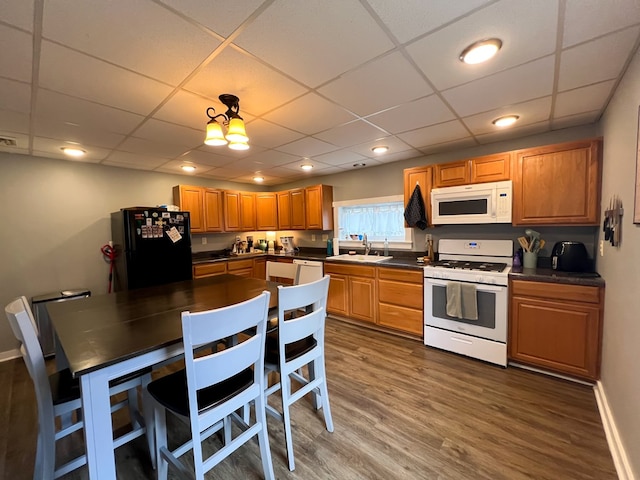 kitchen with white appliances, dark hardwood / wood-style flooring, sink, and a drop ceiling