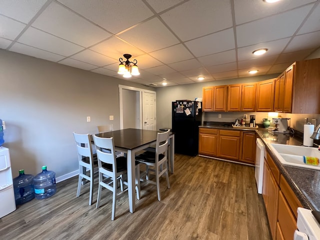 kitchen featuring sink, black fridge, dark hardwood / wood-style floors, dishwasher, and a drop ceiling