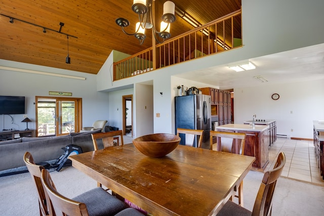 dining space with a towering ceiling, baseboard heating, light tile patterned floors, wooden ceiling, and a notable chandelier