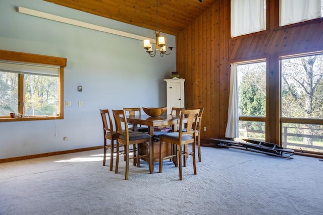 carpeted dining area with a notable chandelier, wood ceiling, and high vaulted ceiling