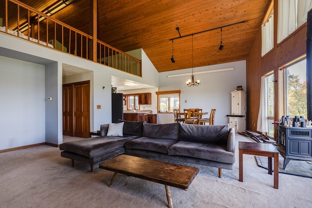 carpeted living room featuring wood ceiling, a high ceiling, and a notable chandelier