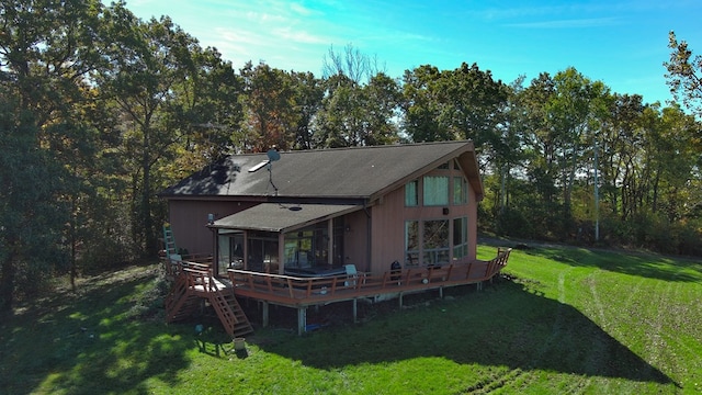 rear view of house with a sunroom, a wooden deck, and a lawn