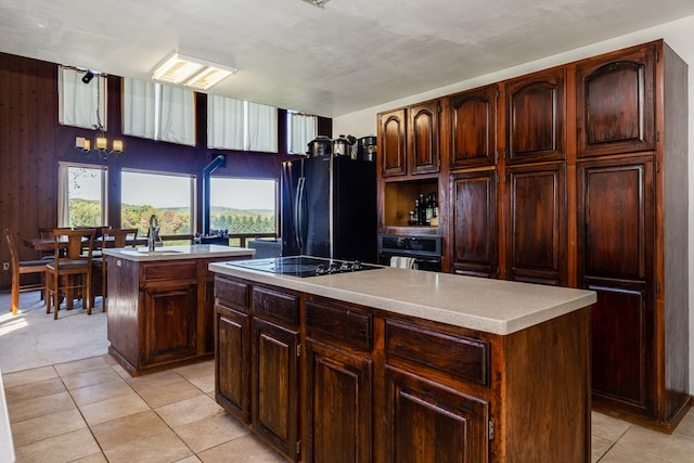 kitchen with a center island, sink, dark brown cabinets, light tile patterned flooring, and black appliances