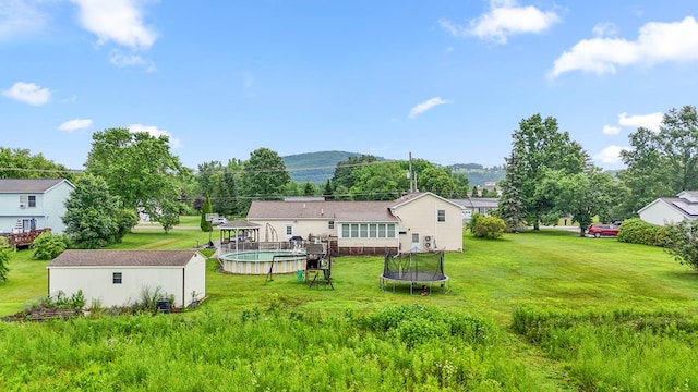 4060 Wilawana Rd, Sayre, PA 18840 - rear view of property featuring a trampoline, a yard, an outdoor pool, an outbuilding, and a mountain view