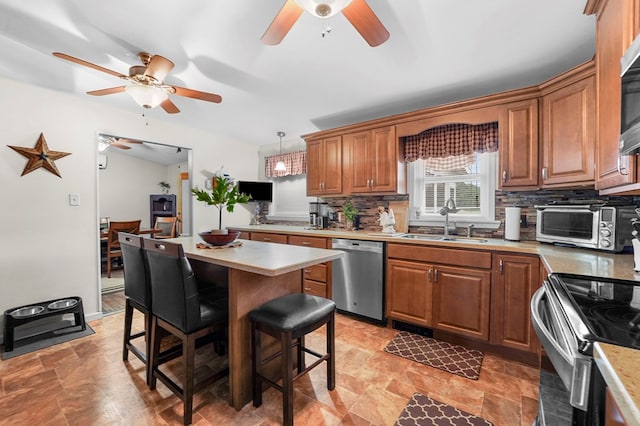 4060 Wilawana Rd, Sayre, PA 18840 - kitchen featuring stainless steel appliances, a ceiling fan, a breakfast bar area, tasteful backsplash, and brown cabinetry
