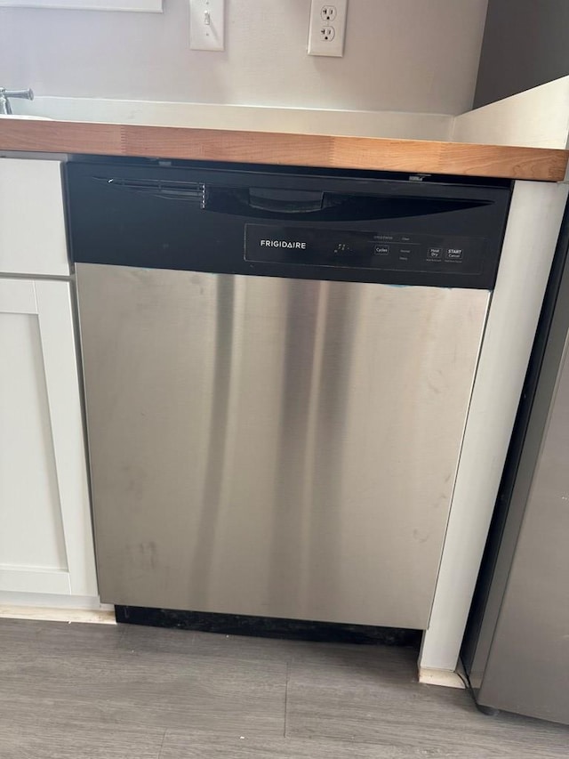 interior details featuring stainless steel dishwasher and light wood-style flooring