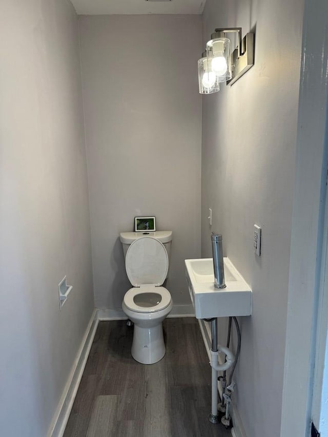 half bathroom with toilet, baseboards, and wood finished floors