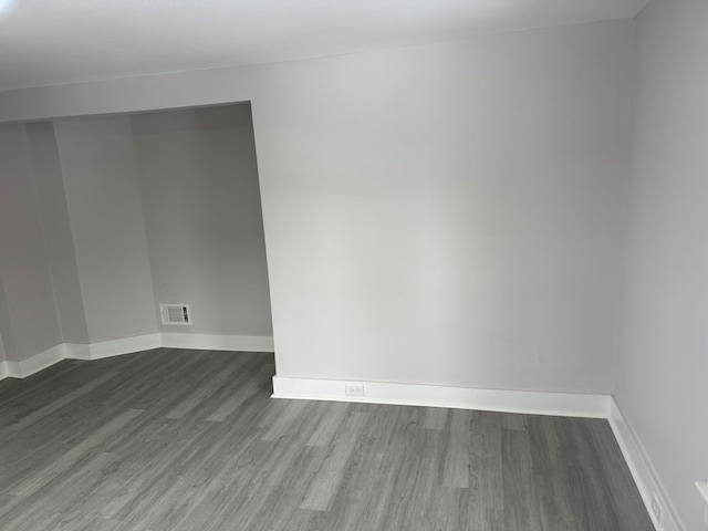 empty room featuring wood finished floors, visible vents, and baseboards