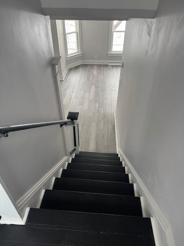 stairs with wood finished floors, baseboards, and a wealth of natural light