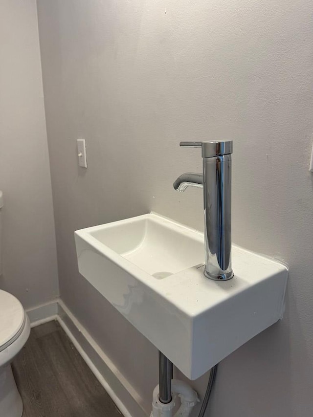 bathroom featuring a sink, toilet, baseboards, and wood finished floors