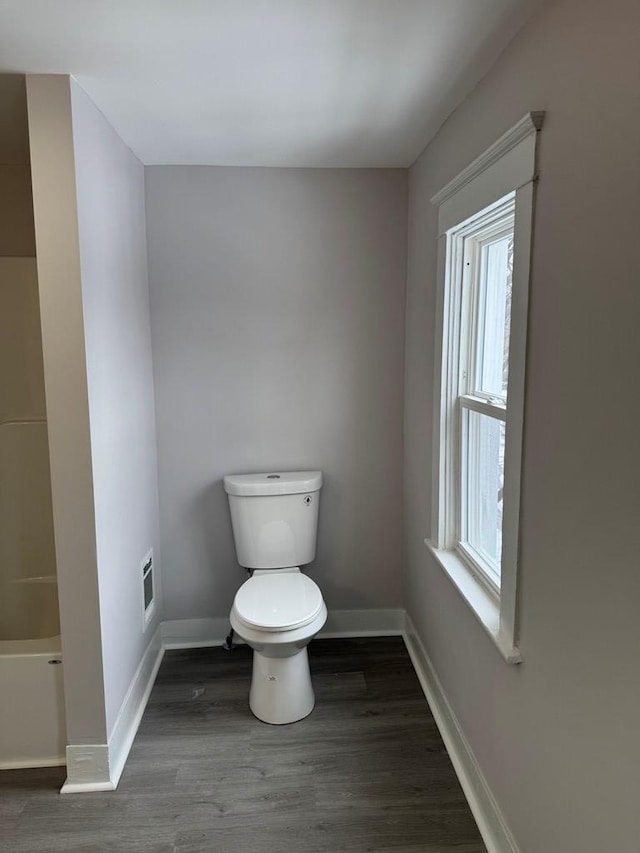 bathroom with a tub, baseboards, toilet, and wood finished floors