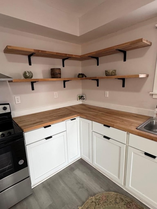 kitchen featuring butcher block countertops, open shelves, a sink, dark wood finished floors, and stainless steel electric range