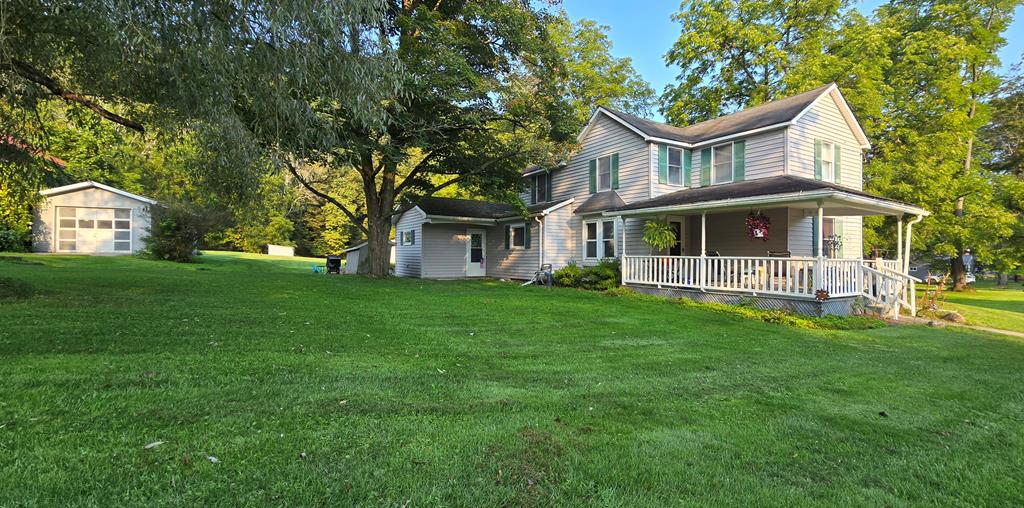 view of side of home featuring a lawn, covered porch, and an outdoor structure