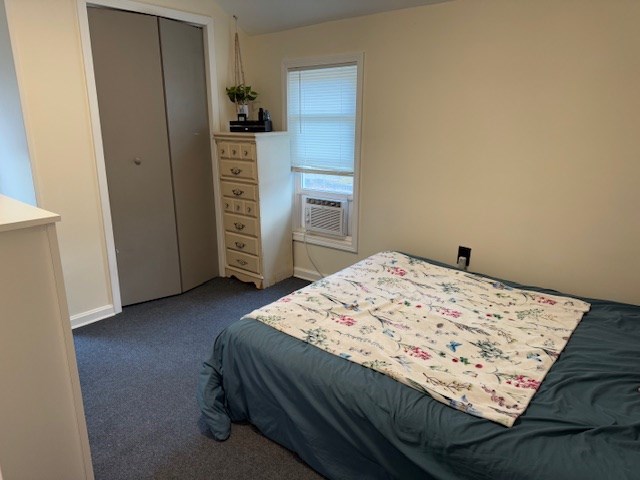 bedroom with dark colored carpet, a closet, and cooling unit