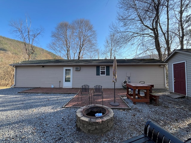 back of property featuring a storage unit, a deck, a fire pit, and an outdoor structure