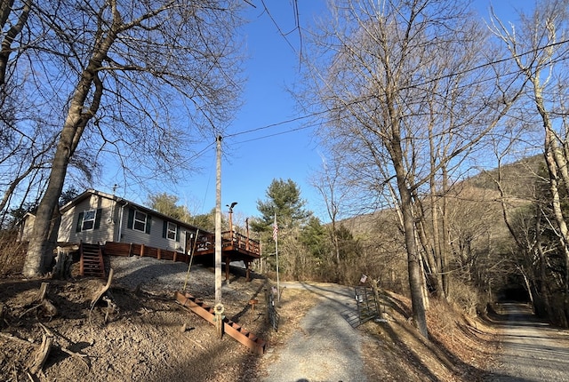 view of front facade with log veneer siding, a deck, and driveway