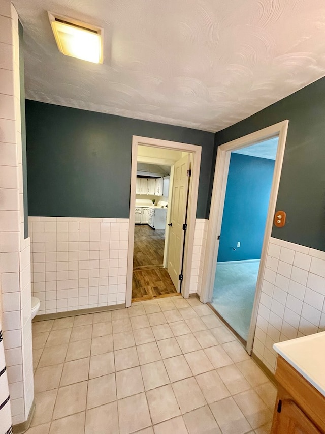 114 Elsbree St, Sayre, PA 18840 - bathroom with a wainscoted wall, tile walls, toilet, tile patterned flooring, and vanity