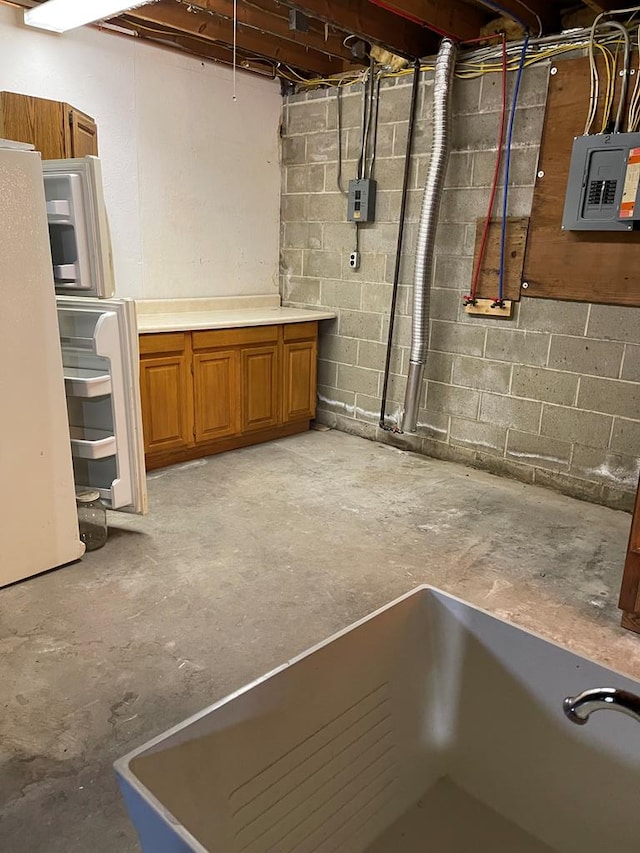 basement featuring electric panel and white fridge