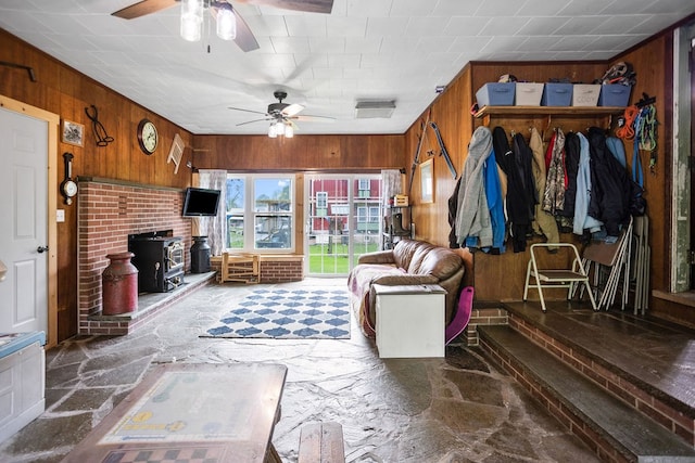 2779 Stony Fork Rd, Wellsboro, PA 16901 - living room featuring stone floors, a ceiling fan, wood walls, and a wood stove